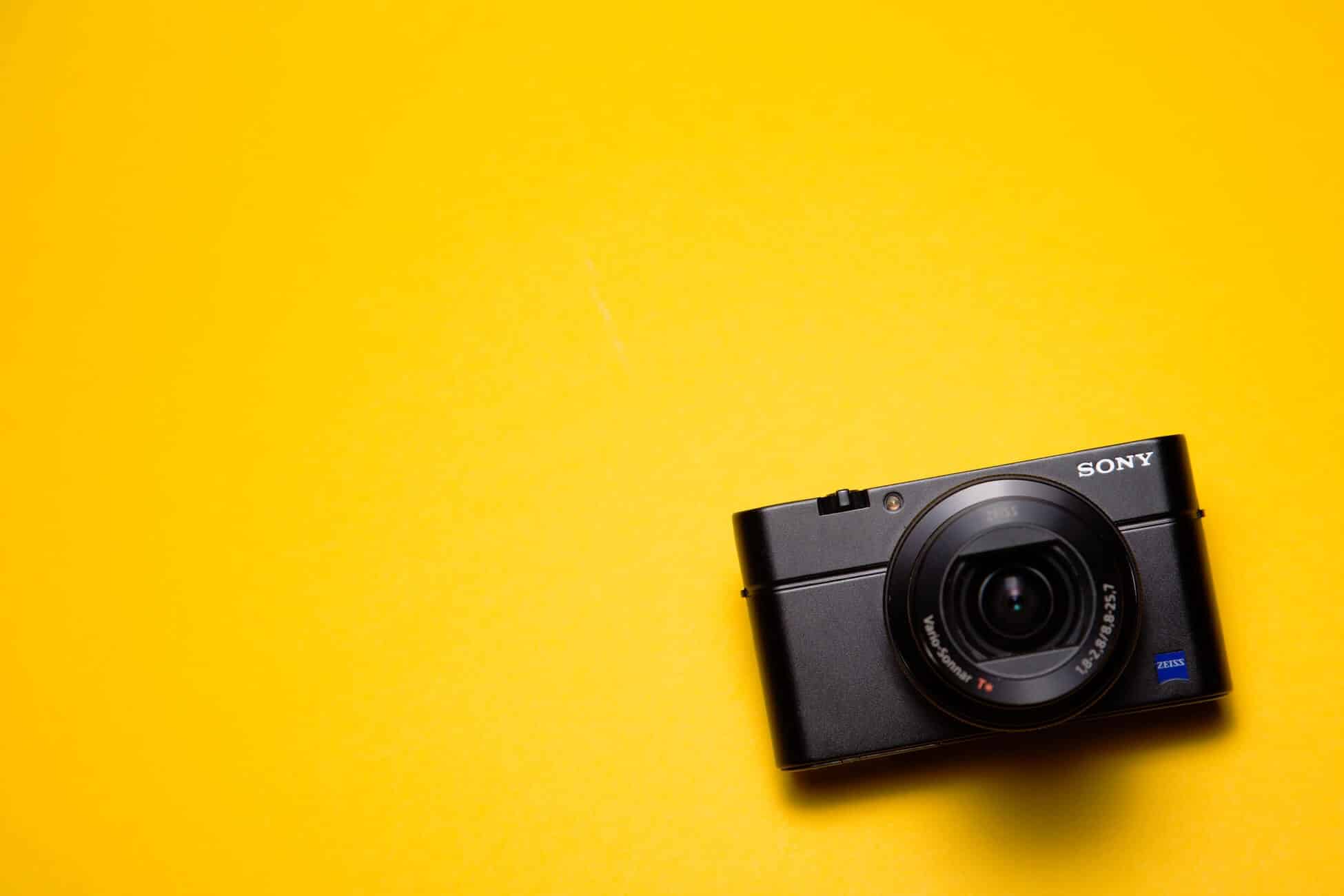 Compactcamera op een gele achtergrond, symbool voor goede woningfoto's die je huis sneller verhuren